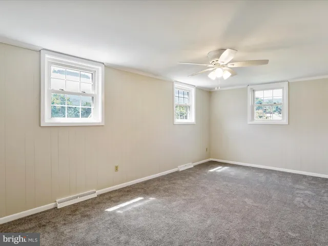 an empty room with chandelier fan and window