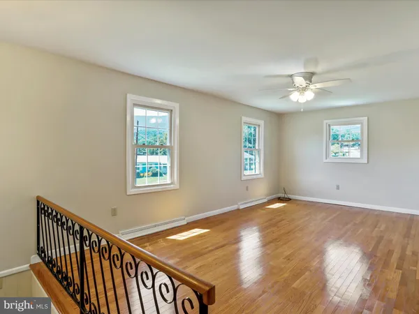 an empty room with wooden floor and fan