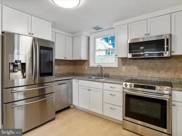 a metallic refrigerator freezer sitting inside of a kitchen