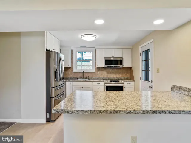 a view of a kitchen with a sink wooden cabinets and a refrigerator