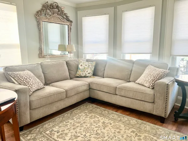 a living room with furniture and a large mirror next to a window