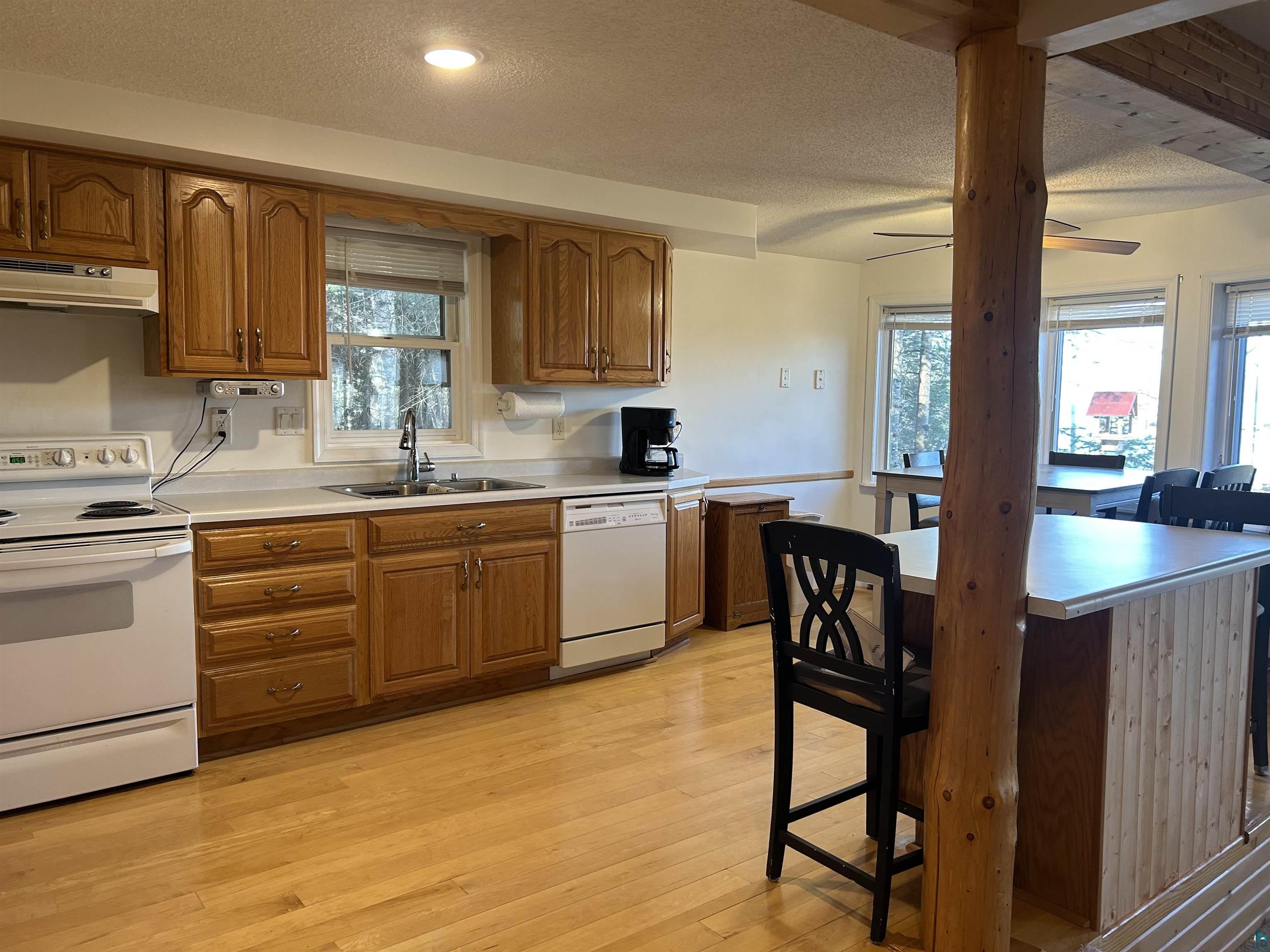 8655 South Lyman Lake Road South Range, WI 54874 - Photo 54 of 64 Kitchen with wood finish cabinets, white appliances, light countertops, light wood-type flooring, and a kitchen bar