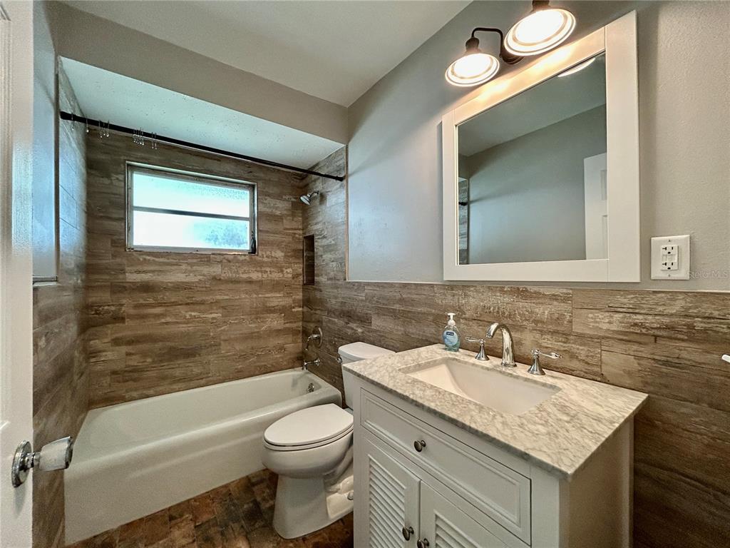 144 175th Avenue East, Unit 1 Redington Shores, FL 33708 - Photo 14 of 15 a bathroom with a granite countertop sink toilet and a bathtub