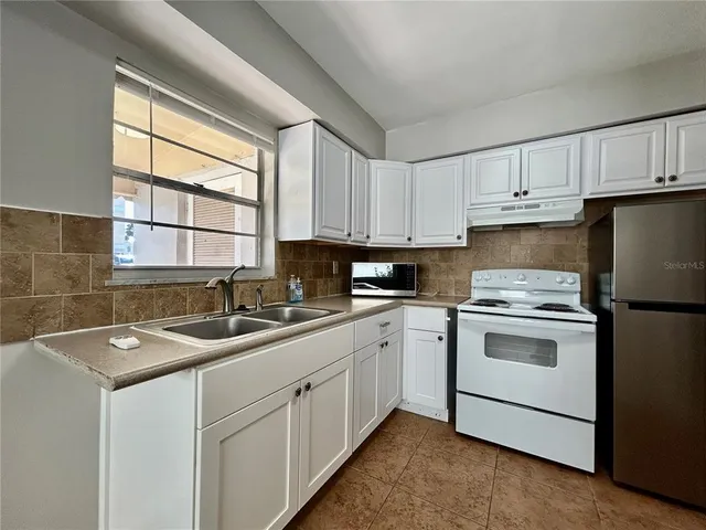 a kitchen with cabinets appliances a sink and a window