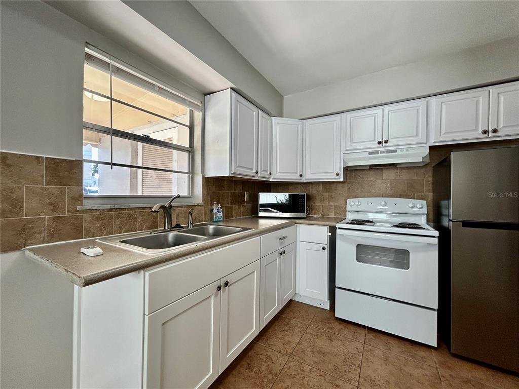 144 175th Avenue East, Unit 1 Redington Shores, FL 33708 - Photo 9 of 15 a kitchen with cabinets appliances a sink and a window