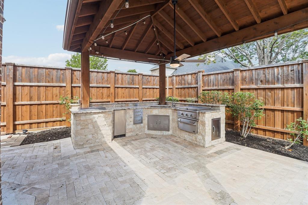 Outdoor kitchen under a covered patio, great for cooking and hosting.