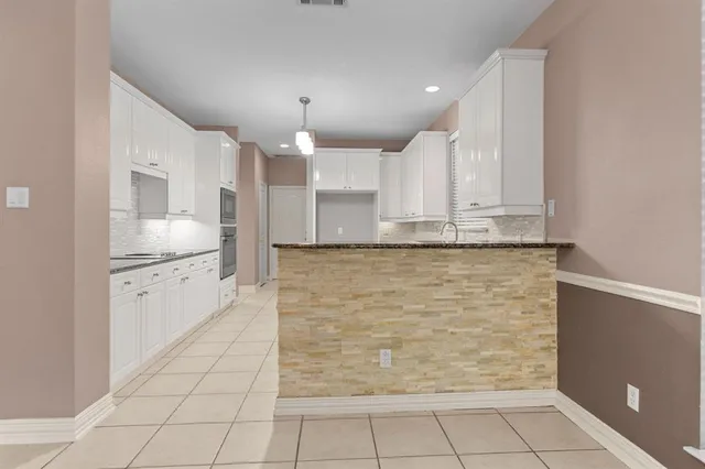 a large white kitchen with kitchen island granite countertop a sink and cabinets
