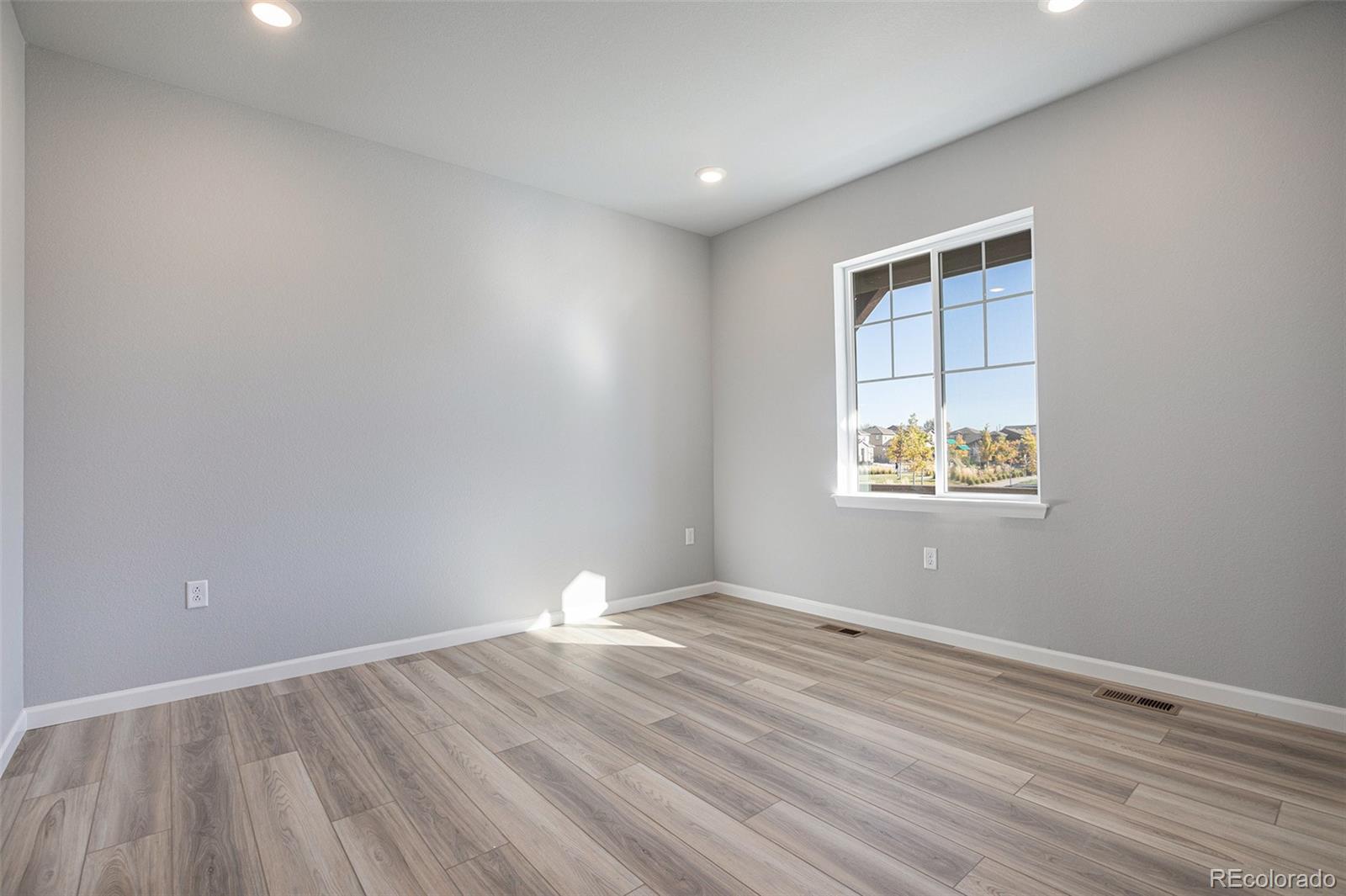 15965 Stringhalt Way Parker, CO 80134 - Photo 16 of 33 an empty room with wooden floor and windows