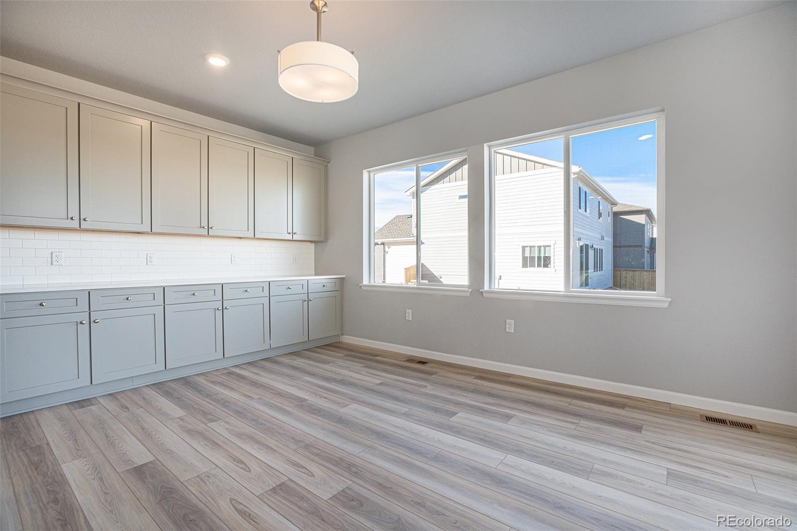 15965 Stringhalt Way Parker, CO 80134 - Photo 10 of 33 a view of a kitchen with dishwasher and white cabinets with wooden floor