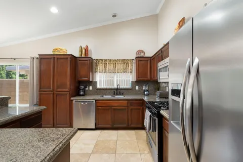 a kitchen with stainless steel appliances granite countertop a refrigerator a sink and a stove