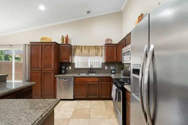 a kitchen with stainless steel appliances granite countertop a refrigerator a sink and a stove
