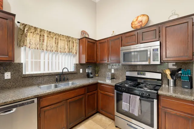 a kitchen with granite countertop a sink a stove a microwave and cabinets