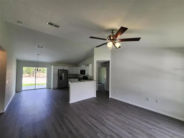 a view of a room with wooden floor and a ceiling fan