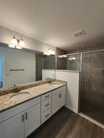 a bathroom with a granite countertop sink a mirror and a shower