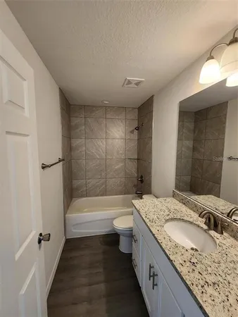 a bathroom with a granite countertop sink a toilet and bathtub