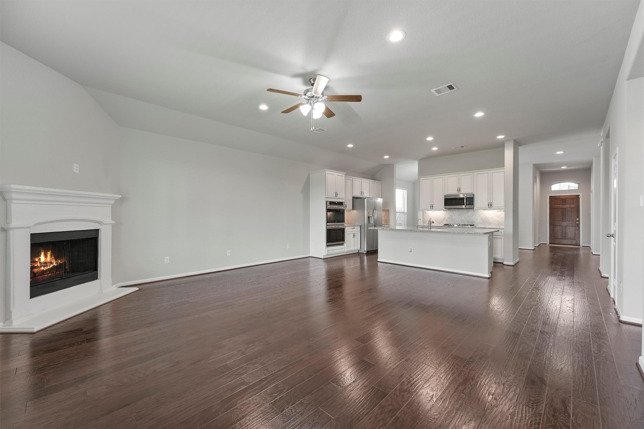 12043 Talmadge Reach Drive Humble, TX 77346 - Photo 14 of 33 a view of an empty room and kitchen with fireplace ceiling fan