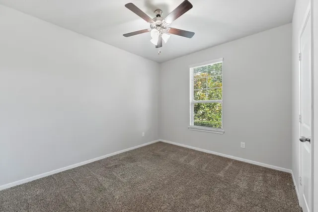 an empty room with windows and ceiling fan