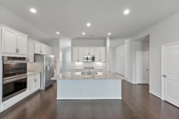 a view of kitchen with stainless steel appliances refrigerator stove microwave and cabinets