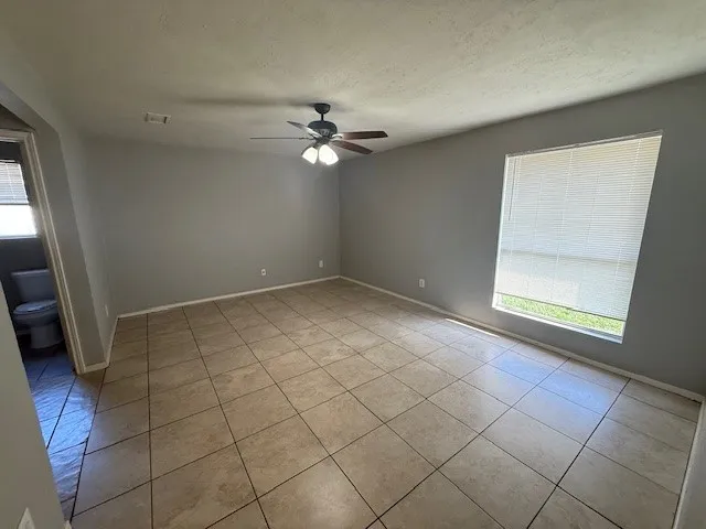 an empty room with a ceiling fan and window
