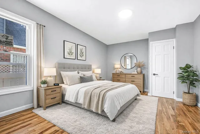 a bedroom with a bed a potted plant on dresser and a window