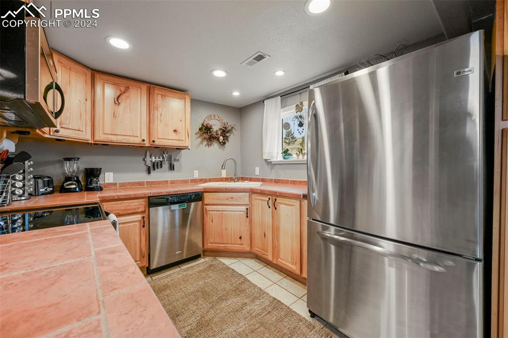 608 Slater Creek Road Guffey, CO 80820 - Photo 19 of 47 a kitchen with stainless steel appliances granite countertop a refrigerator a sink dishwasher a stove with white cabinets and wooden floor