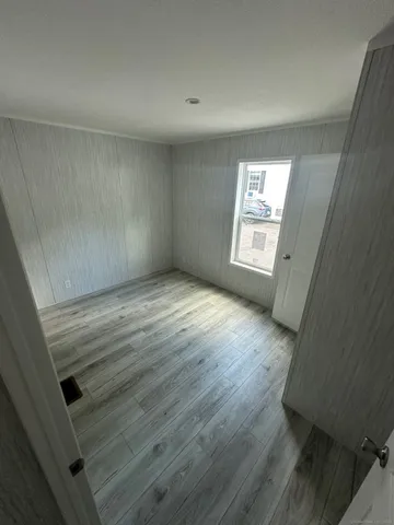 a view of an empty room with wooden floor and window