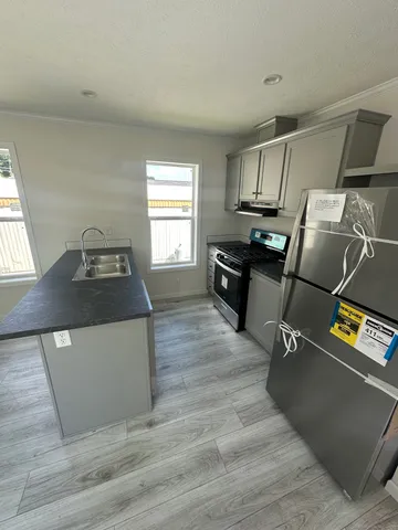 a kitchen with granite countertop a refrigerator and a stove top oven
