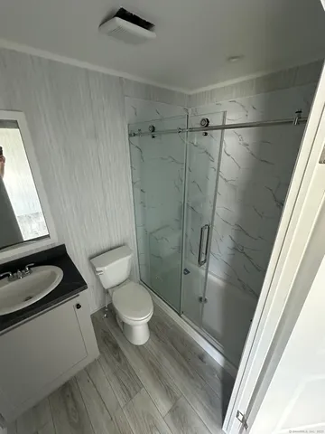 a bathroom with a granite countertop toilet a sink and shower