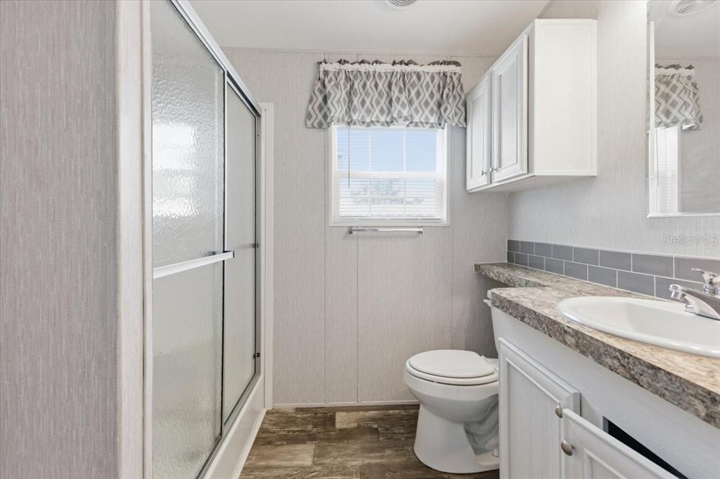 1800 Englewood Road, Unit 166 Englewood, FL 34223 - Photo 18 of 34 a bathroom with a granite countertop toilet a sink and a mirror