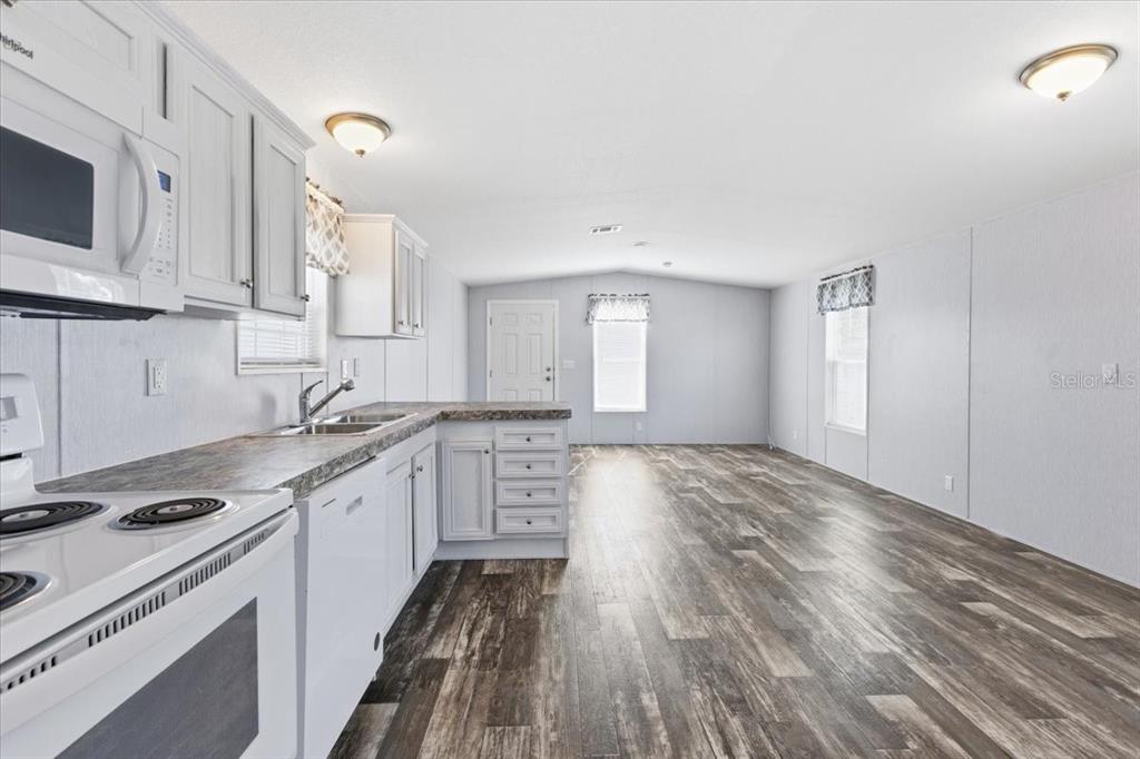 1800 Englewood Road, Unit 166 Englewood, FL 34223 - Photo 6 of 34 a kitchen with granite countertop a stove top oven sink and cabinets