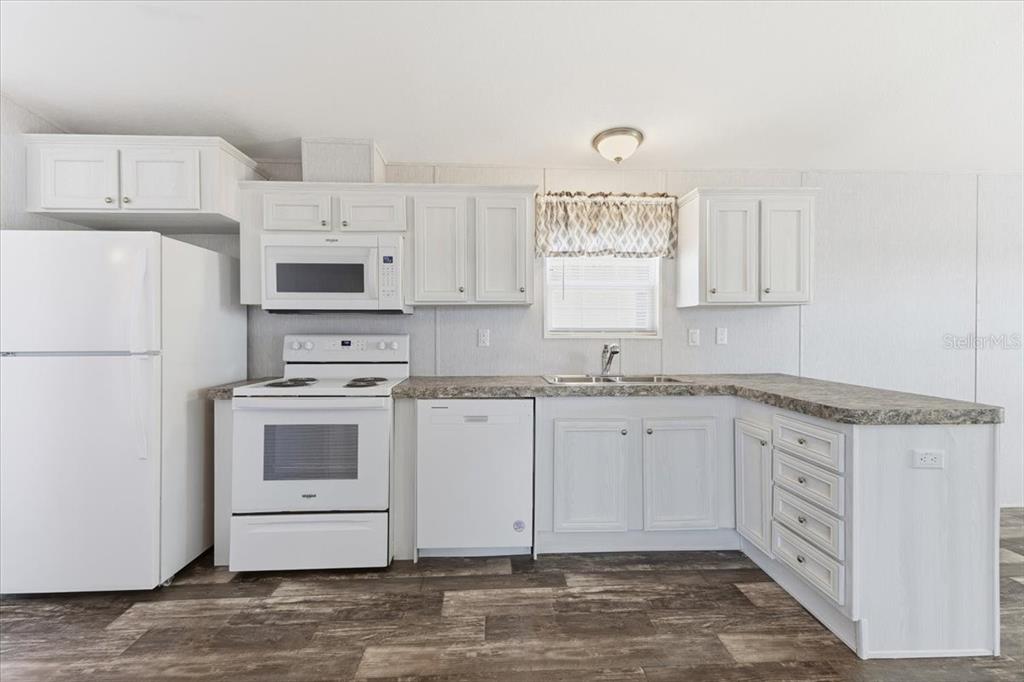 1800 Englewood Road, Unit 166 Englewood, FL 34223 - Photo 7 of 34 a kitchen with granite countertop a sink stainless steel appliances and white cabinets