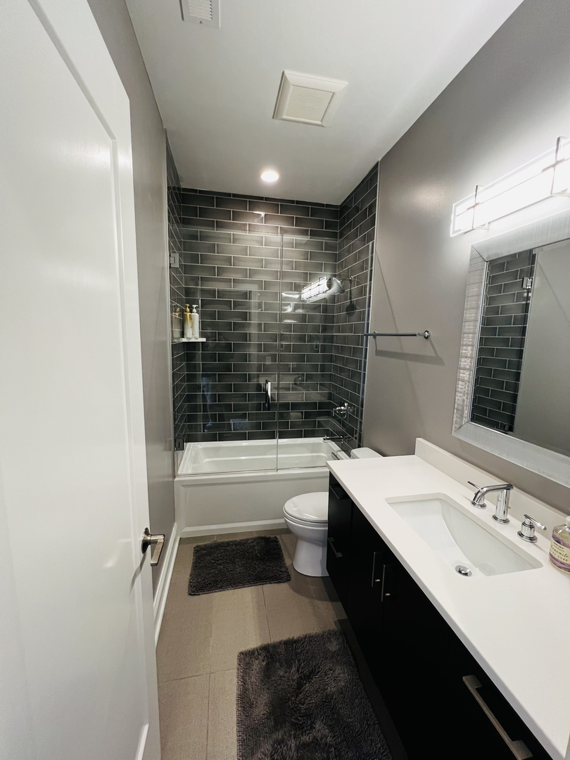 2946 North Racine Avenue, Unit 2 Chicago, IL 60657 - Photo 11 of 17 a bathroom with a double vanity sink toilet bathtub and mirror