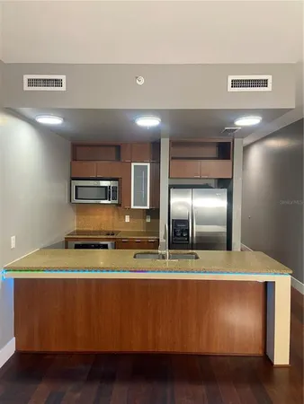 a view of a kitchen with stainless steel appliances granite countertop a stove a sink and a refrigerator