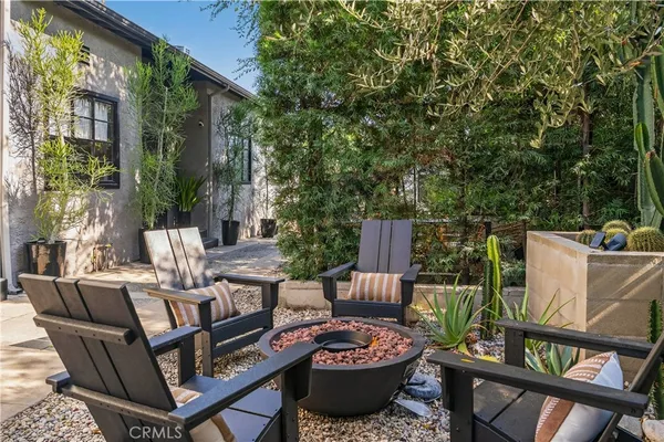 a view of a patio with couches potted plants and a large tree