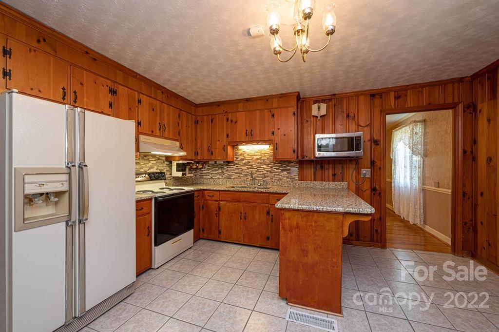 4254 Hartland Road Lenoir, NC 28645 - Photo 21 of 47 a kitchen with stainless steel appliances granite countertop a refrigerator a sink a stove a dining table and chairs