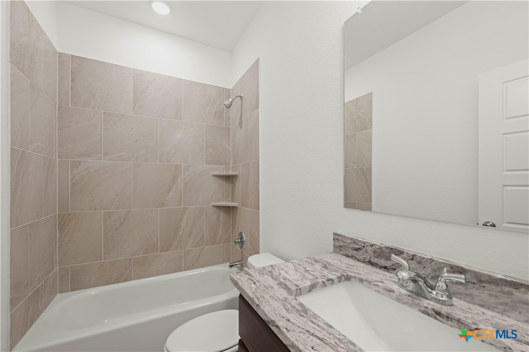 7715 Krenek Tap Drive Temple, TX 76502 - Photo 11 of 30 a bathroom with a granite countertop sink a toilet and bathtub