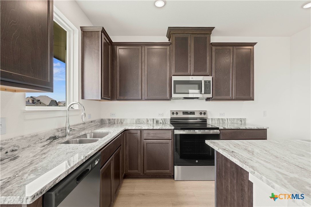 7715 Krenek Tap Drive Temple, TX 76502 - Photo 27 of 30 a kitchen with stainless steel appliances granite countertop a sink stove and microwave