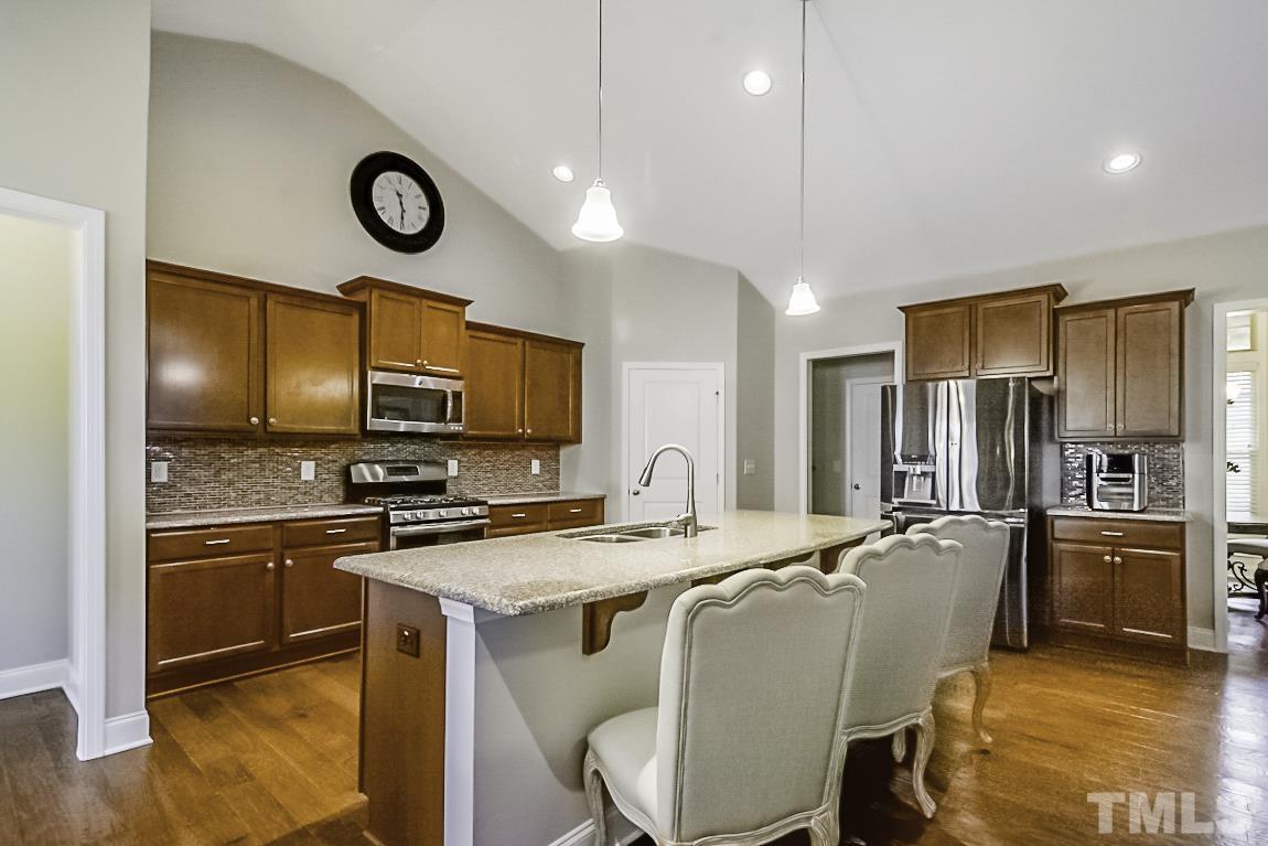7617 Channery Way Raleigh, NC 27616 - Photo 14 of 42 a kitchen with stainless steel appliances granite countertop a stove top oven a refrigerator a sink and a dining table with chairs