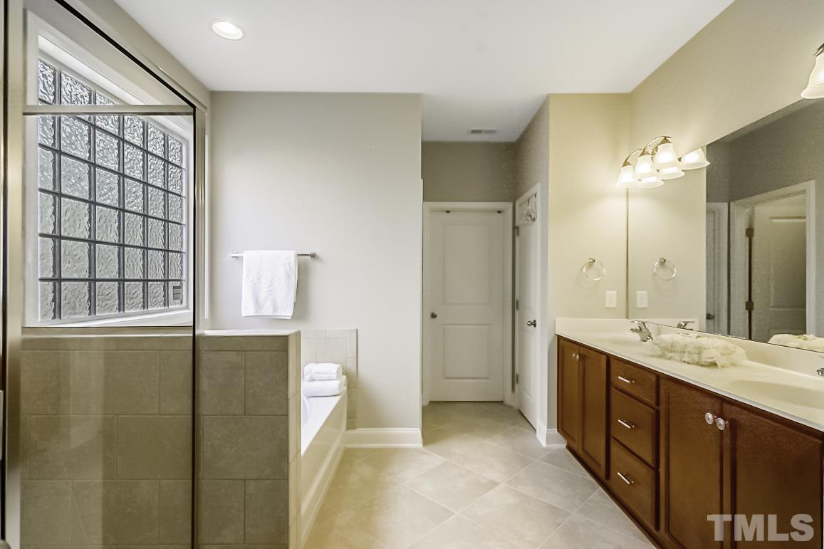 7617 Channery Way Raleigh, NC 27616 - Photo 22 of 42 a spacious bathroom with a double vanity sink a large mirror and a shower