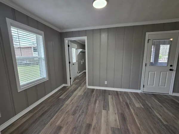 an empty room with wooden floor and windows