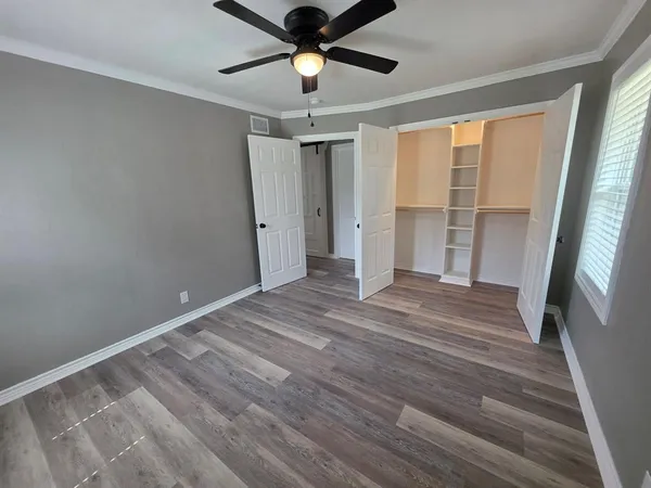a view of empty room with wooden floor and fan