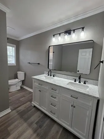 a spacious bathroom with double vanity sink a mirror and lamp