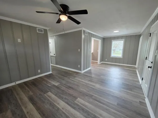 a view of empty room with wooden floor and fan