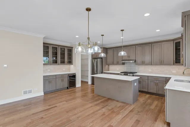 a large kitchen with kitchen island a stove a sink a center island and wooden floor