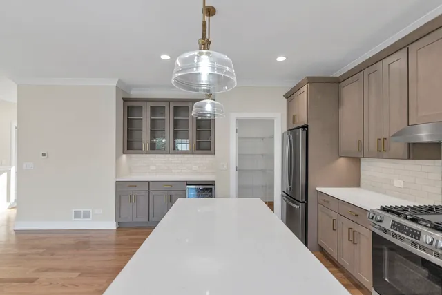 a open kitchen with stainless steel appliances granite countertop a refrigerator a stove and a wooden floors