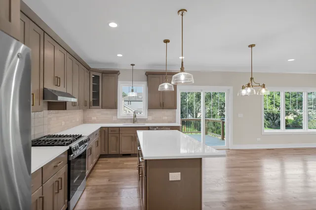 a kitchen with stainless steel appliances granite countertop a stove a sink and a wooden floor