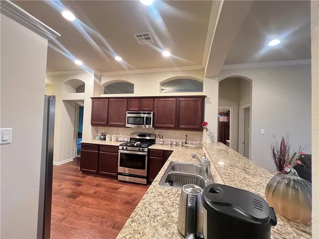 a kitchen with stainless steel appliances granite countertop a stove refrigerator and a sink