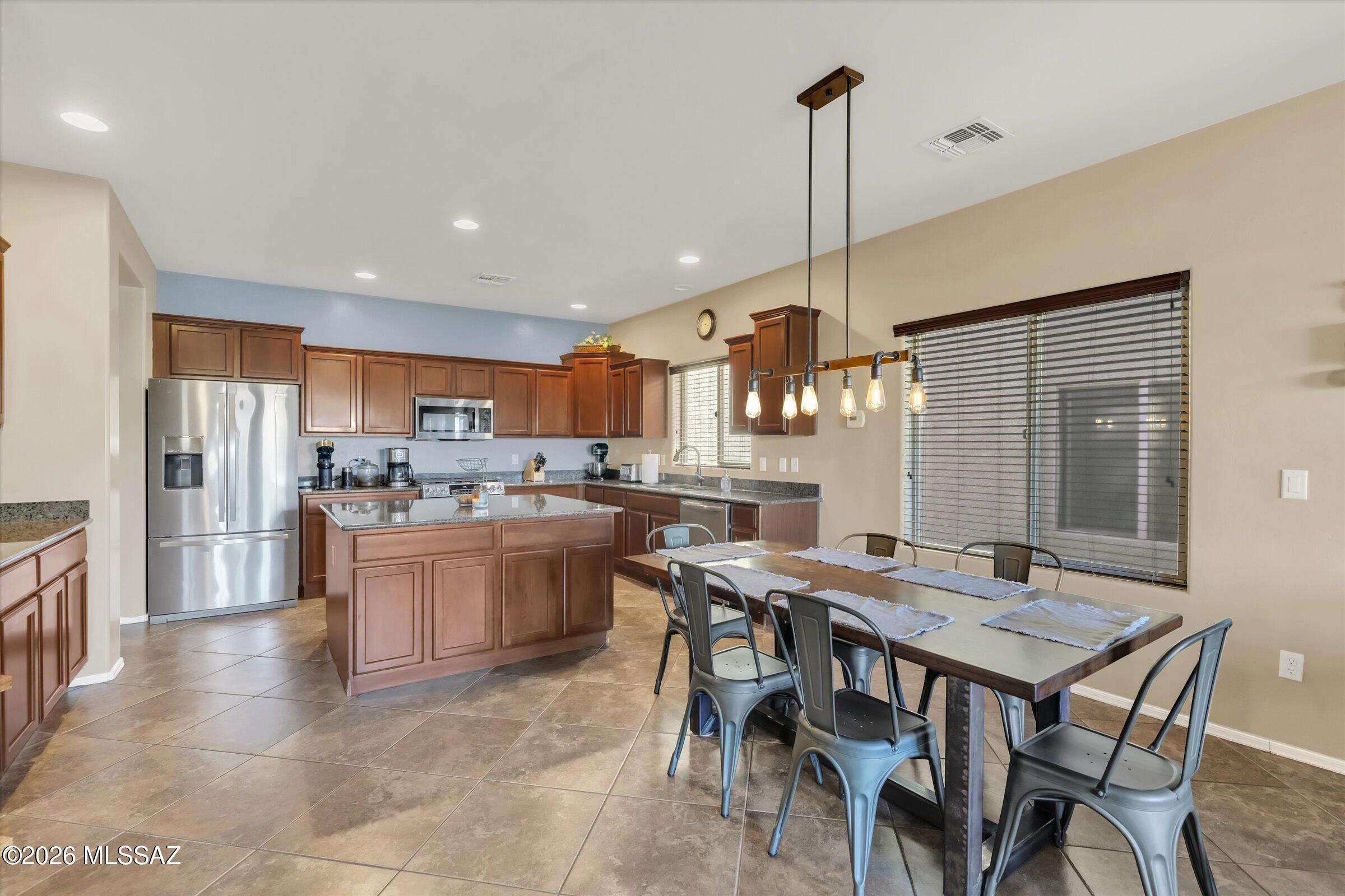 6095 South Jakemp Trail Tucson, AZ 85747 - Photo 19 of 52 a kitchen with kitchen island a dining table chairs stainless steel appliances and cabinets