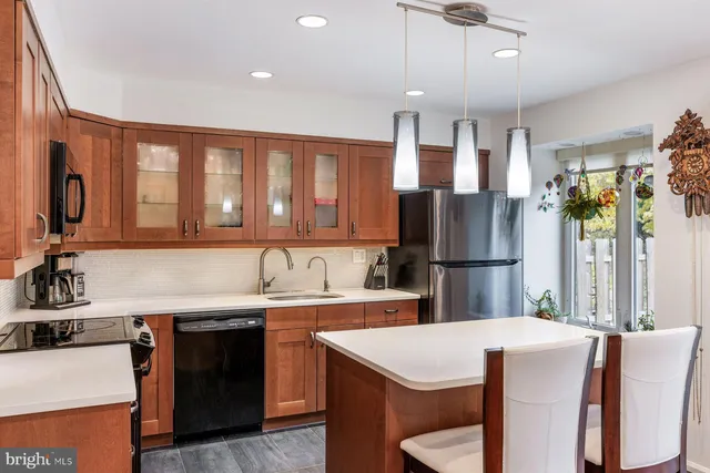 a kitchen with stainless steel appliances kitchen island granite countertop a sink a stove a refrigerator a dining table and chairs with wooden floor