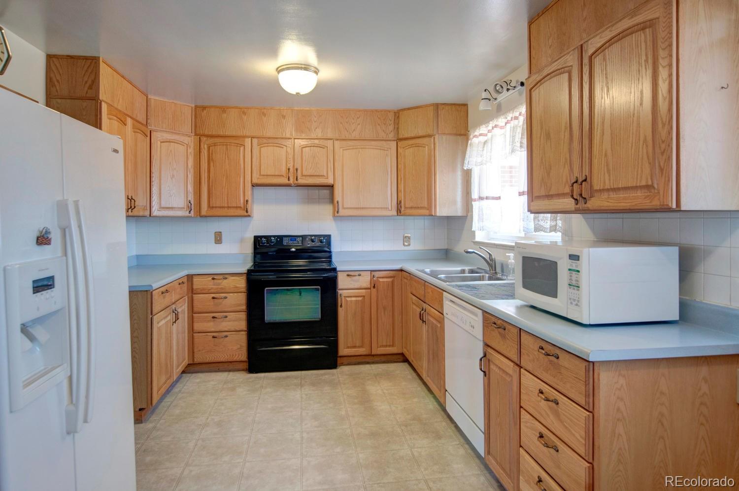 4581 Reed Street Wheat Ridge, CO 80033 - Photo 6 of 29 a kitchen with stainless steel appliances granite countertop a stove a sink and a refrigerator